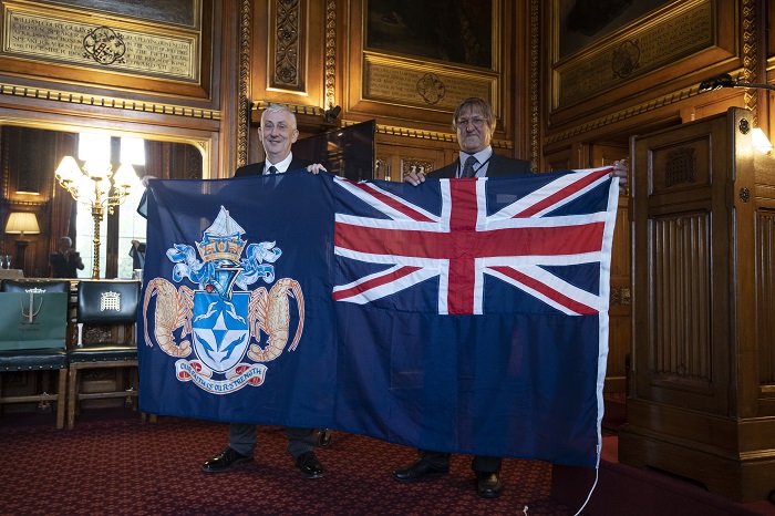 A Tristan flag was given to the Speaker, who holds it up with James Glass