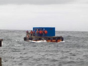 The container with the bulls is ferried ashore on the raft.