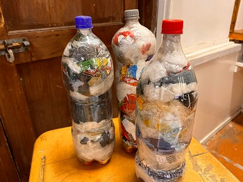 Plastic bottles stuffed with snack wrappers, to be used as ecobricks. The kids want to build something with them, dog house or something