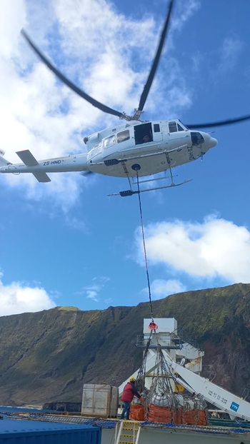 Helicopter preparing to lift cargo from the deck of the ship.