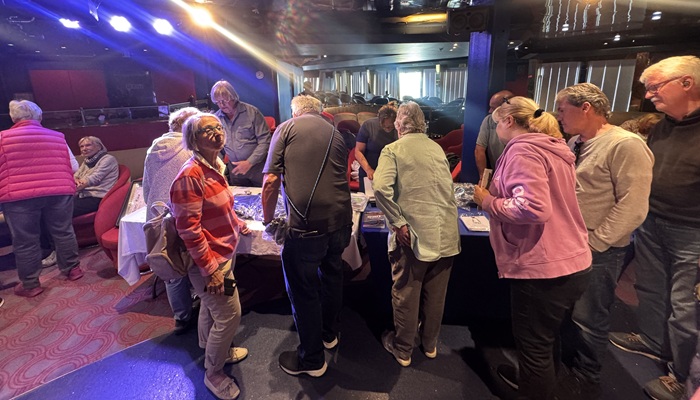 Passengers throng the Rockhopper Gift Shop's stall in the ship's lounge.