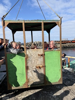 Passengers being hoisted in the box onto the raft for embarkation on the departing Lance.