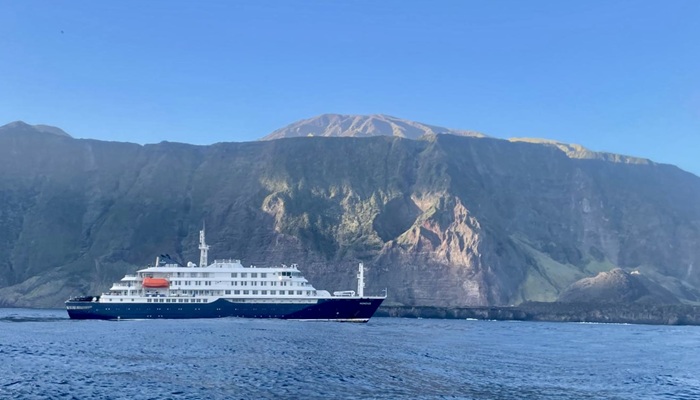 The MV Hondius off Pigbite with the island cliffs and the Peak in the background, and the 1961 volcanic cone in the foreground at the right. Photo: Philip Kendall