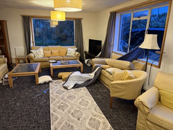 The main Residency living room, drenched and scattered with broken window glass.