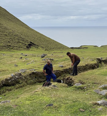 Two hunters check a possible rat lair in a gulley.