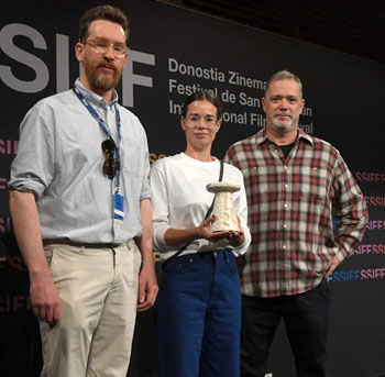Actress Laia Costa presents the Greenpeace Lurra Award at the 2026 San Sebastián International Film Festival to the film “Tristan Forever,” co-directed by Loran Bonnardot and Tobias Nölle. Tobias Nölle and the producer of the fictional documentary, Christof Neracher, accept the award and are shown here with Laia Costa.