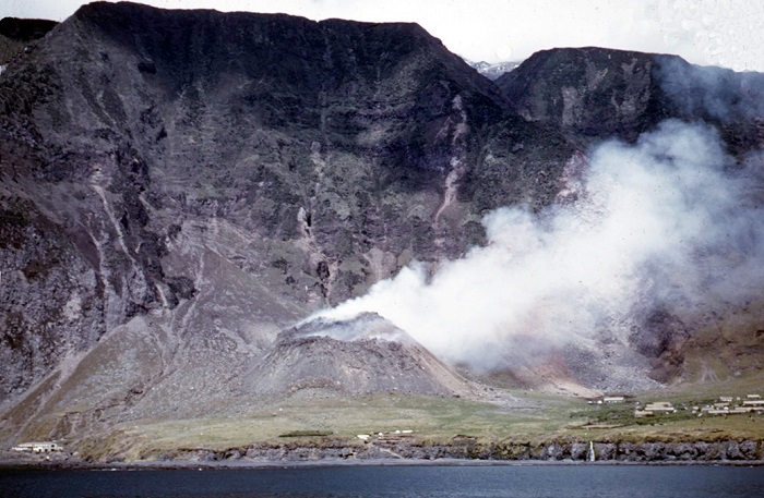Still from a film shot from HMS Leopard showing the volcano in its early stages behind the settlement