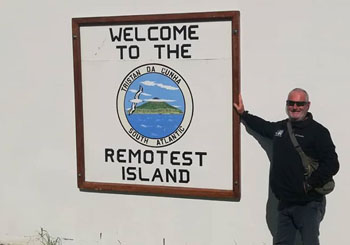 Yacht Ronin crew member at the Remotest Island sign.