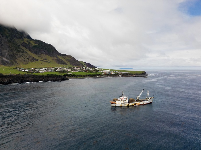 A drone shot of the MFV Edinburgh off the settlement before she departed, with Inaccessible Island on the horizon